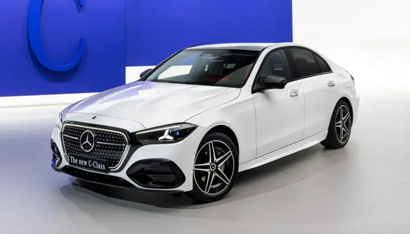 Biały sedan marki Daimler, nowy C-Klasa, prezentuje się elegancko na tle niebieskiego logo.