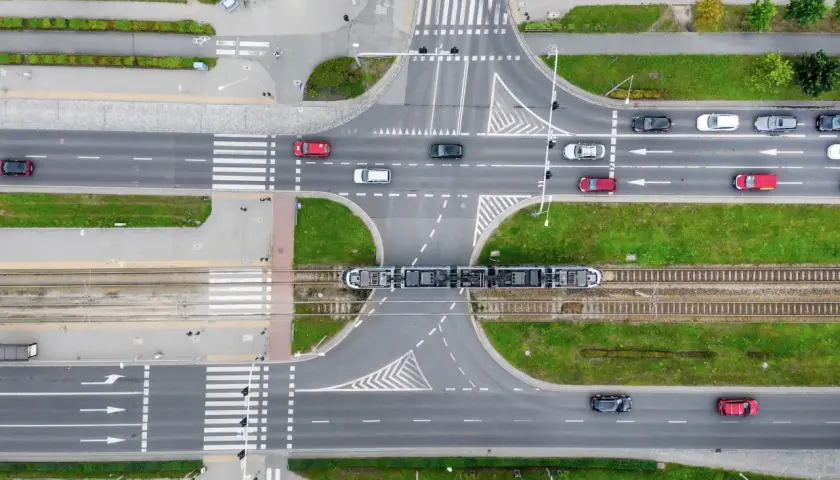 Widok z góry na skrzyżowanie z tramwajem i samochodami. Zastanawiasz się, ile metrów od skrzyżowania można parkować? Przepisy drogowe określają to precyzyjnie.