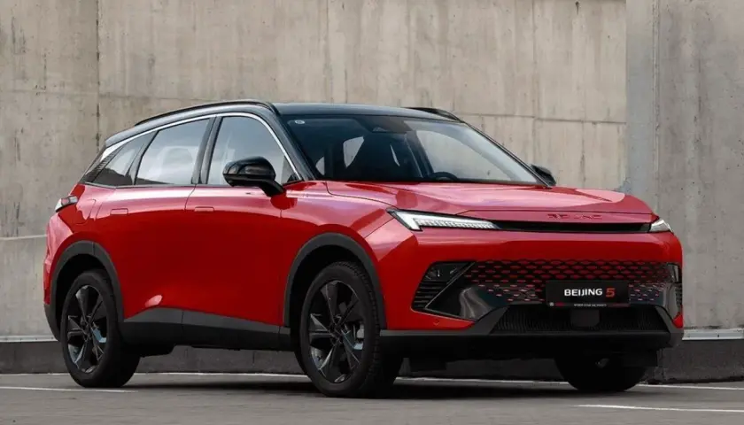 Czerwony BAIC 5, SUV o futurystycznym designie, prezentuje swoje pięć wymiarów na tle betonowej ściany.