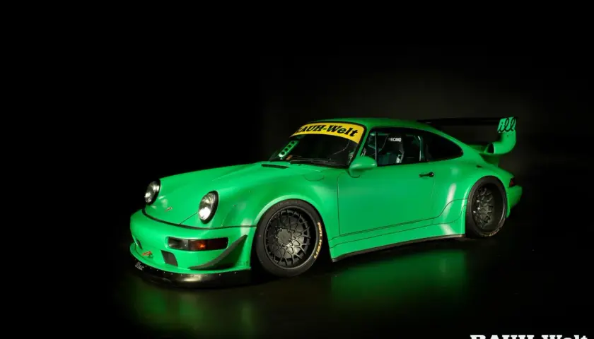 Jaskrawozielone Porsche RWB z szerokimi błotnikami i charakterystycznym skrzydłem, gotowe do wyścigu.