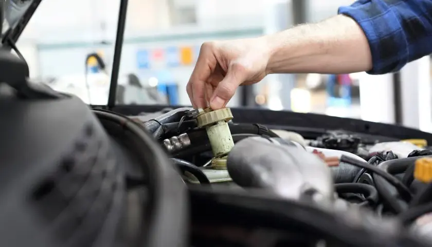 Mechanik sprawdza płyn hamulcowy. Czas na badanie techniczne po terminie, by uniknąć problemów.