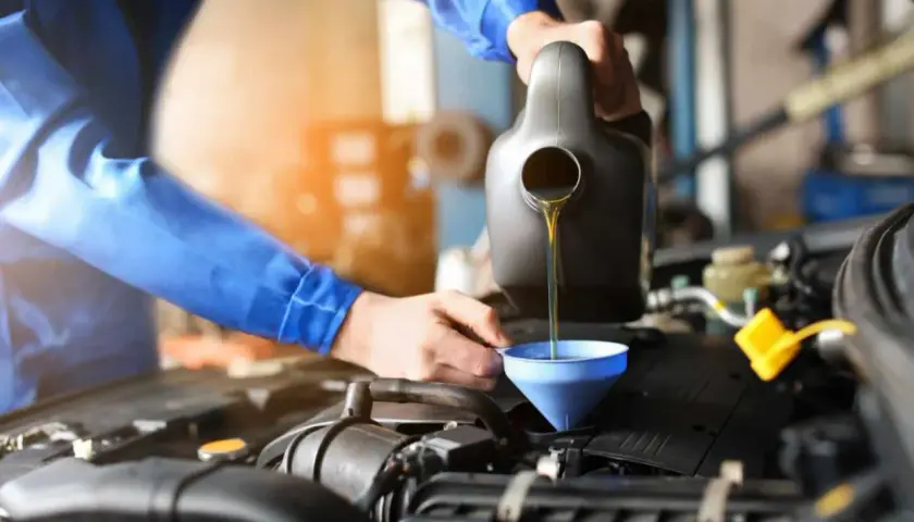Mechanik wlewa olej do silnika. Pamiętaj o regularnej wymianie oleju, co ile to konieczne dla sprawnego działania auta.