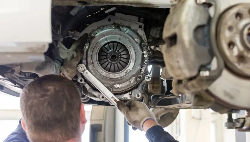 Mechanik dokonuje wymiany sprzęgła w samochodzie, używając klucza dynamometrycznego do precyzyjnego dokręcenia śrub.