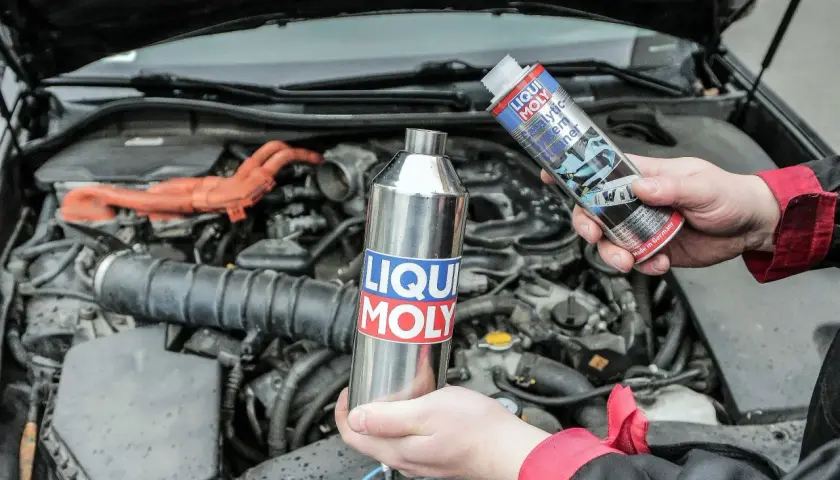 Ręce trzymają preparaty Liqui Moly do czyszczenia układu paliwowego, by zapobiec objawom zapchanego katalizatora.
