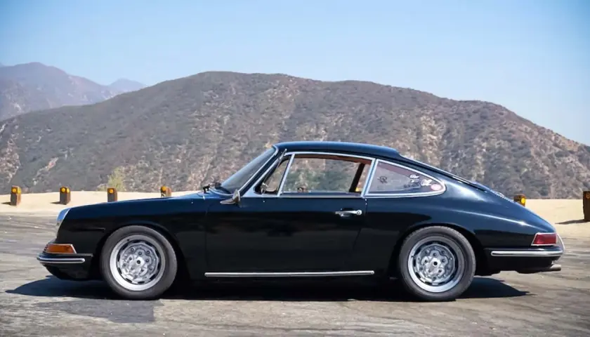 Klasyczny czarny Porsche 912 z lat 60. na tle górskich krajobrazów.