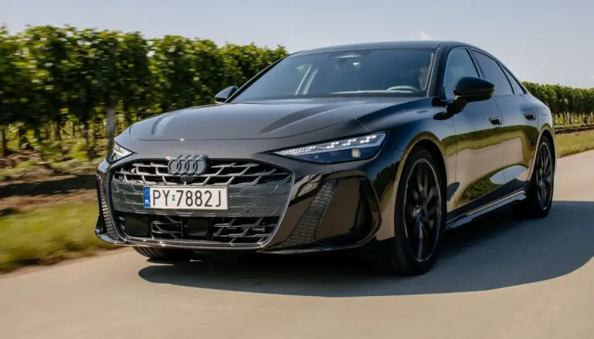 Eleganckie, czarne Audi A6 C9 w ruchu, z grillem i reflektorami w pełnej krasie, na tle zielonych winnic.