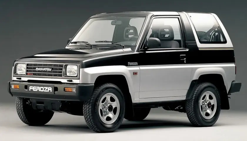 Dwukolorowy Daihatsu Feroza, klasyczny samochód terenowy z lat 90., prezentuje się na szarym tle.
