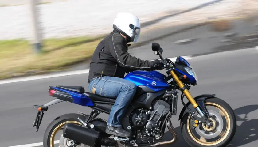 Motocyklista w białym kasku pędzi na niebieskim motocyklu Yamaha FZ8.
