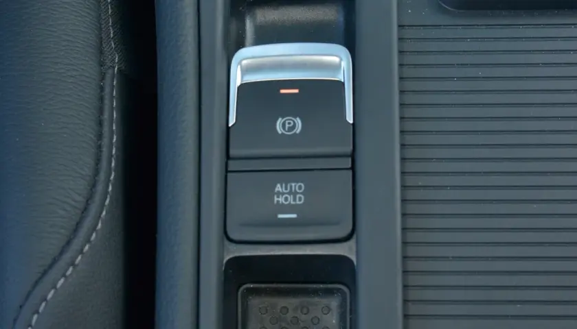 Przycisk "AUTO HOLD" w samochodzie, obok hamulca ręcznego.