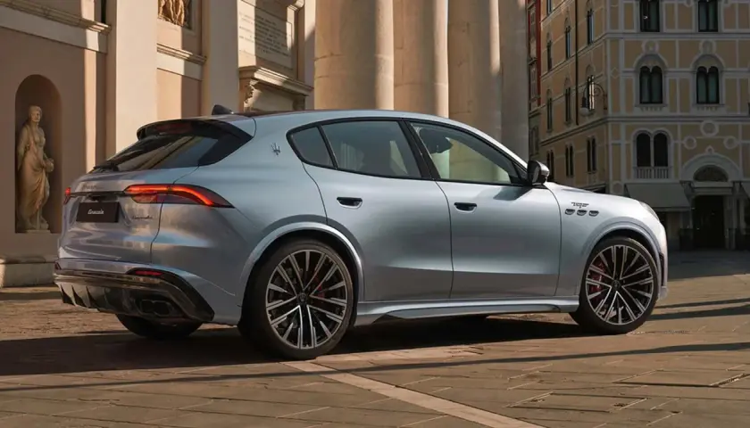 Srebrny Maserati Grecale z eleganckimi felgami stoi na brukowanej ulicy przed zabytkową kamienicą.