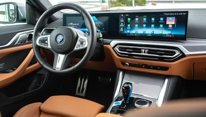 Wnętrze BMW M440i z brązową skórzaną tapicerką, dużym ekranem multimedialnym i cyfrowymi zegarami.