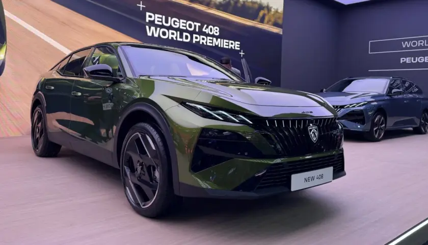 Nowy Peugeot 408 w kolorze zielonym prezentuje się na premierze światowej. Obok stoi niebieski egzemplarz.