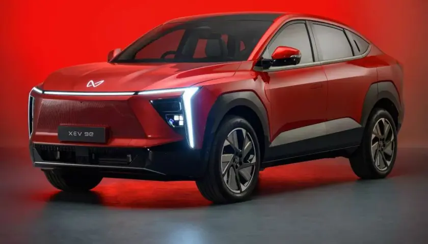 Czerwony, elektryczny SUV Mahindra XUV 9e z futurystycznym designem i podświetlanym grillem.