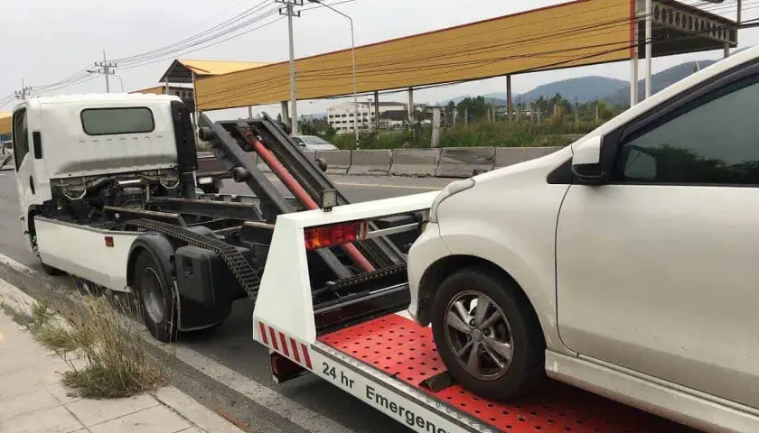 Pomoc drogowa w akcji: białe auto jest ładowane na lawetę. Widać mechanizm, jak holować auto, by bezpiecznie przetransportować pojazd.