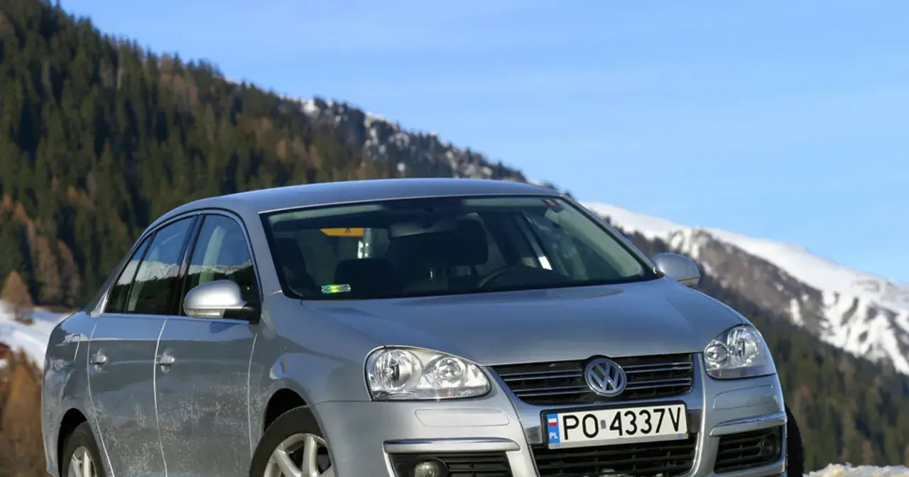 Srebrna Jetta MK5 na tle ośnieżonych gór i lasu.
