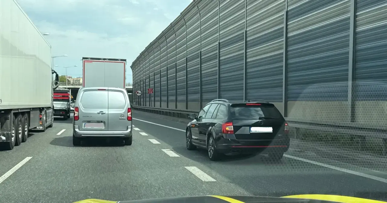 Kork na autostradzie, samochody stoją w rzędzie. Kierowcy czekają na możliwość jazdy na suwak, by płynnie włączyć się do ruchu.