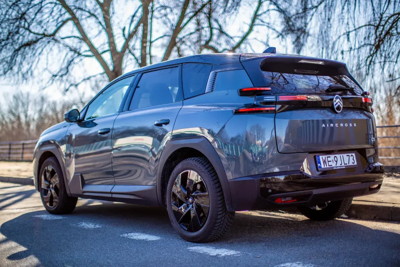 Ciemnoszary Citroen C5 Aircross, nowoczesny citroen suv, zaparkowany na tle drzew.
