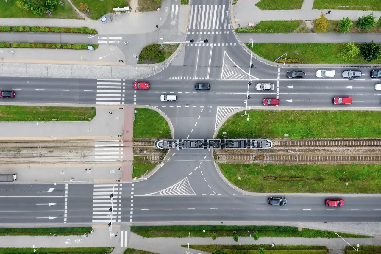 Widok z góry na skrzyżowanie z tramwajem i samochodami. Zastanawiasz się, ile metrów od skrzyżowania można parkować? Przepisy drogowe określają to precyzyjnie.