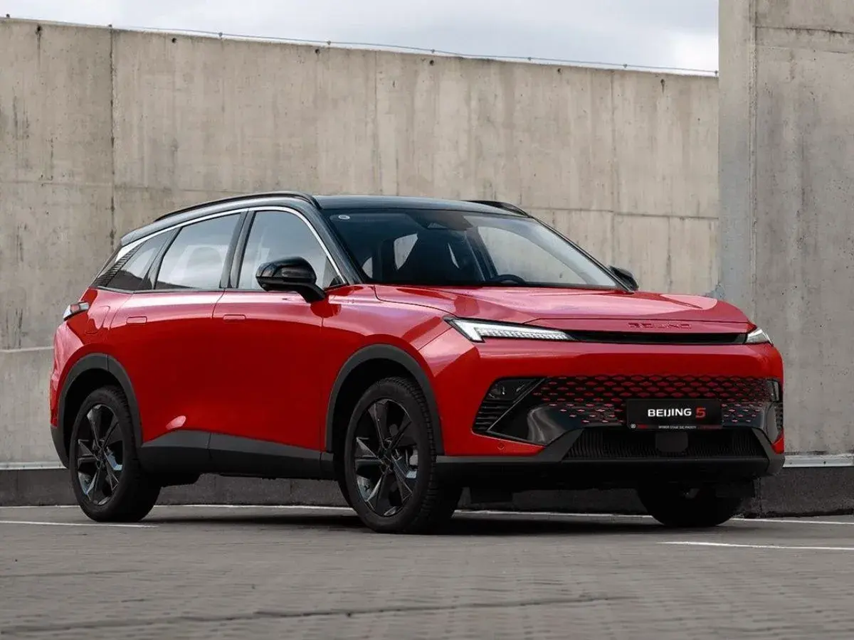 Czerwony BAIC 5, SUV o futurystycznym designie, prezentuje swoje pięć wymiarów na tle betonowej ściany.