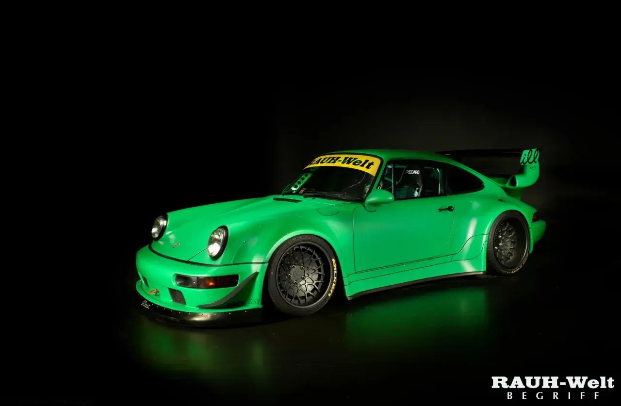 Jaskrawozielone Porsche RWB z szerokimi błotnikami i charakterystycznym skrzydłem, gotowe do wyścigu.
