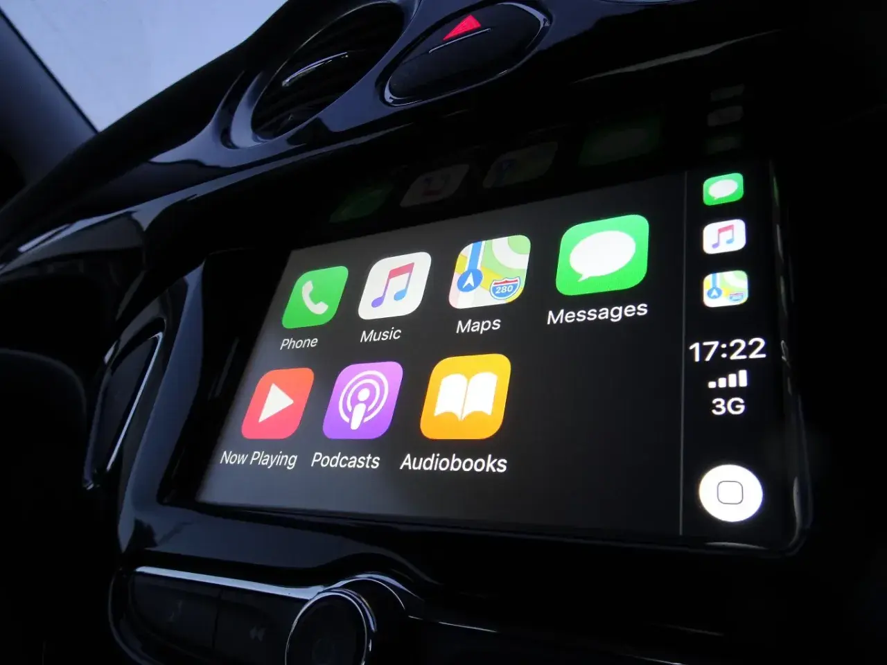 Ekran samochodu z ikonami: Telefon, Muzyka, Mapy, Wiadomości, Odtwarzanie, Podcasty, Audiobooki. To jest właśnie co to jest CarPlay.