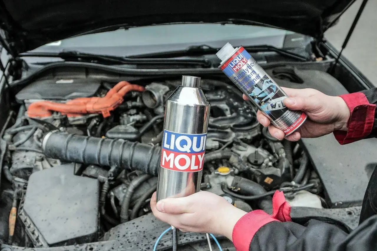 Ręce trzymają preparaty Liqui Moly do czyszczenia układu paliwowego, by zapobiec objawom zapchanego katalizatora.