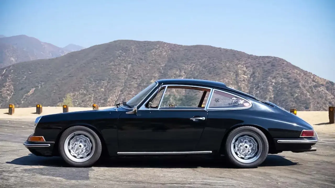 Klasyczny czarny Porsche 912 z lat 60. na tle górskich krajobrazów.