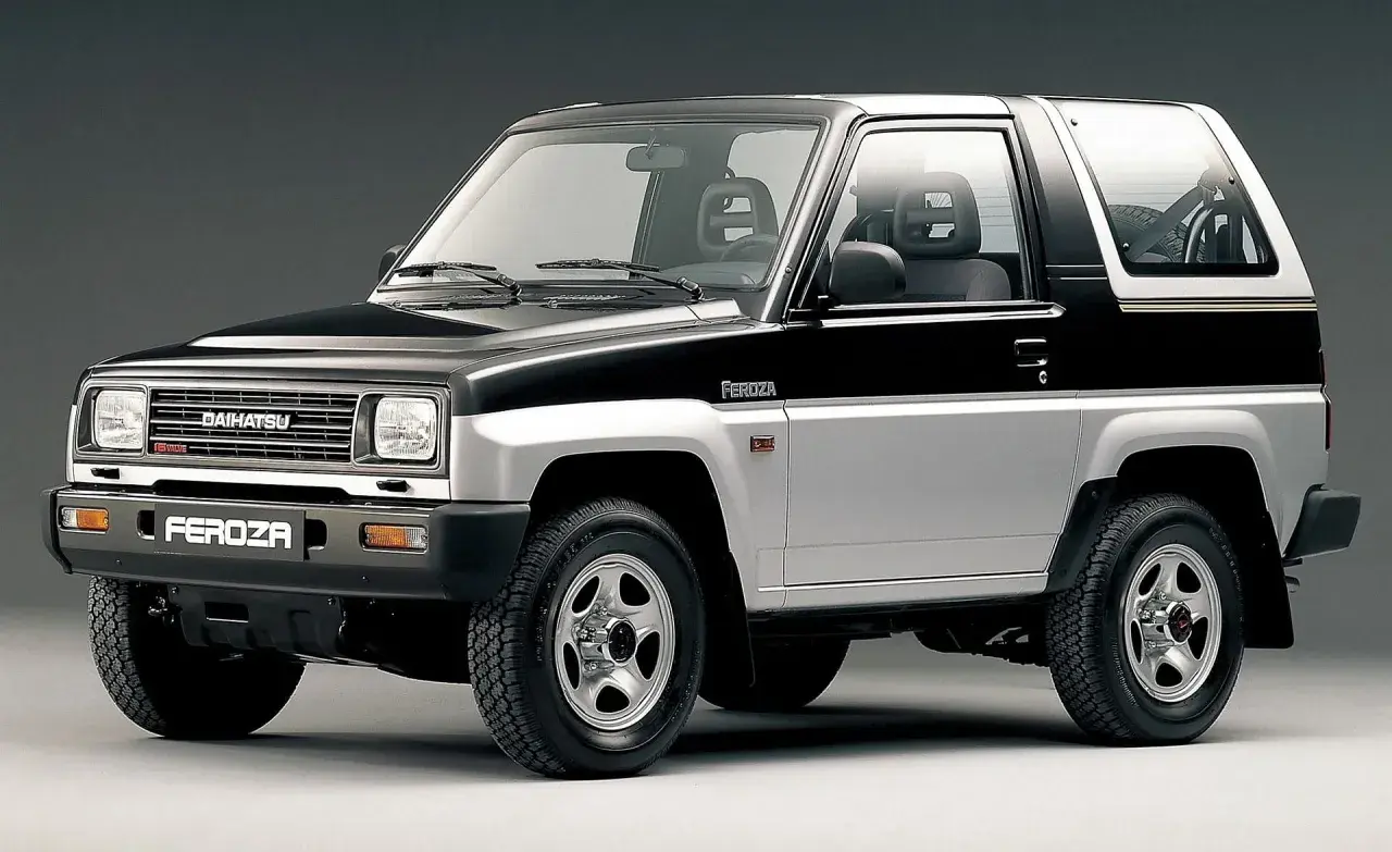 Dwukolorowy Daihatsu Feroza, klasyczny samochód terenowy z lat 90., prezentuje się na szarym tle.