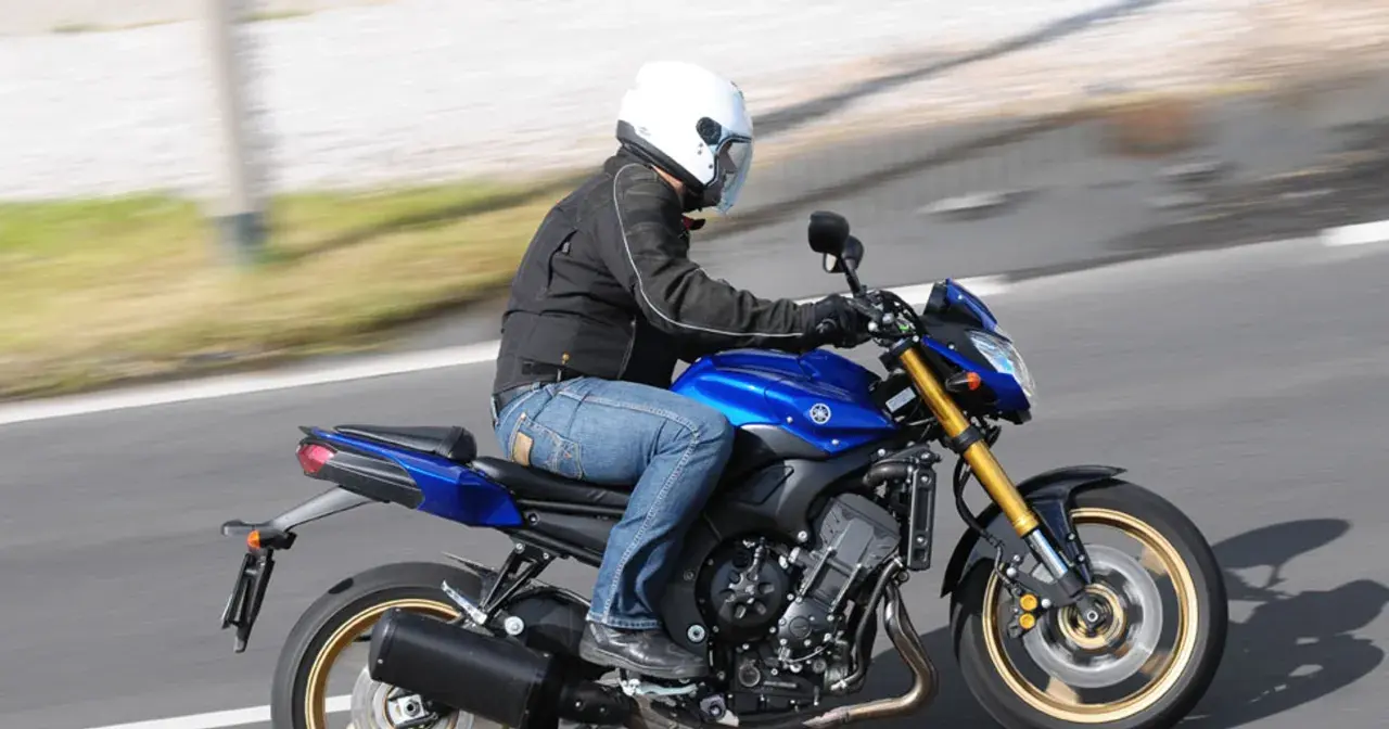 Motocyklista w białym kasku pędzi na niebieskim motocyklu Yamaha FZ8.