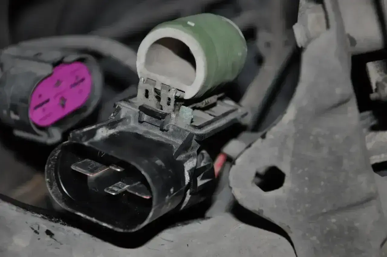 Zielony opornik ceramiczny z metalowymi zaciskami, podłączony do złącza elektrycznego.