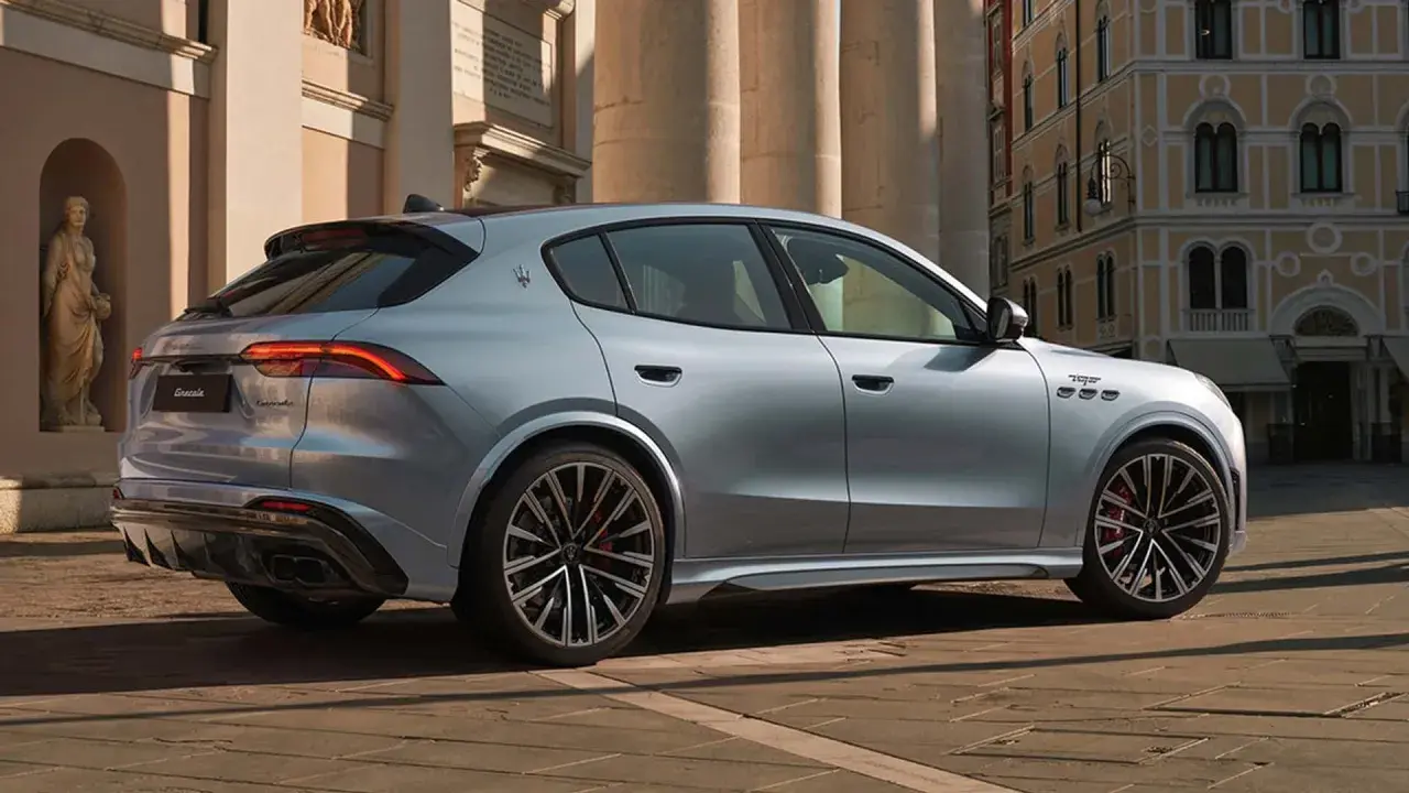 Srebrny Maserati Grecale z eleganckimi felgami stoi na brukowanej ulicy przed zabytkową kamienicą.