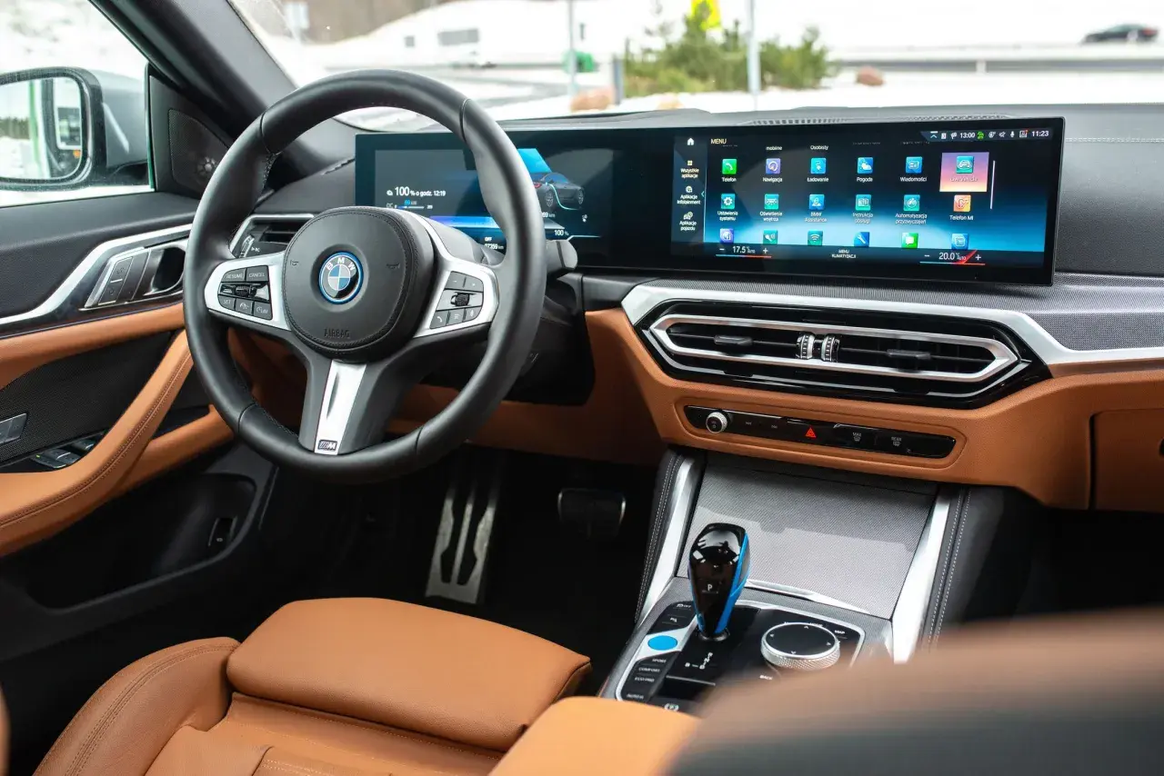 Wnętrze BMW M440i z brązową skórzaną tapicerką, dużym ekranem multimedialnym i cyfrowymi zegarami.