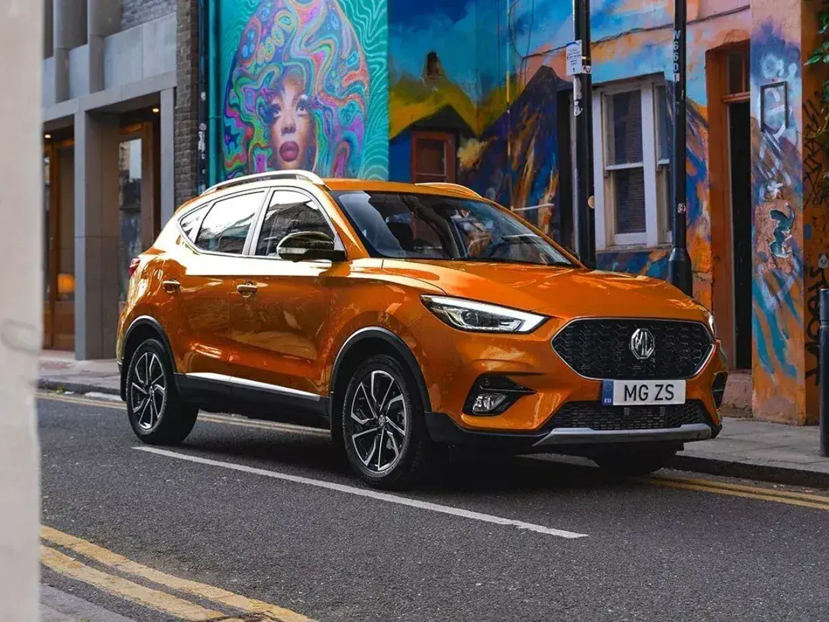 Pomarańczowy MG ZS Classic na tle kolorowego muralu.