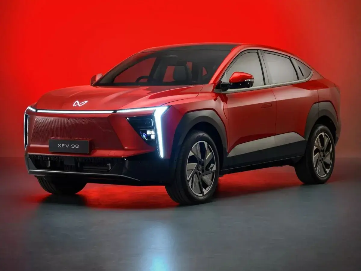 Czerwony, elektryczny SUV Mahindra XUV 9e z futurystycznym designem i podświetlanym grillem.