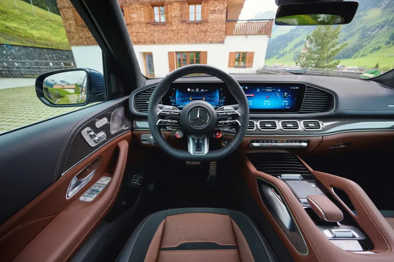 Wnętrze luksusowego Mercedes GLE 53 AMG z brązową skórzaną tapicerką i nowoczesnymi ekranami.