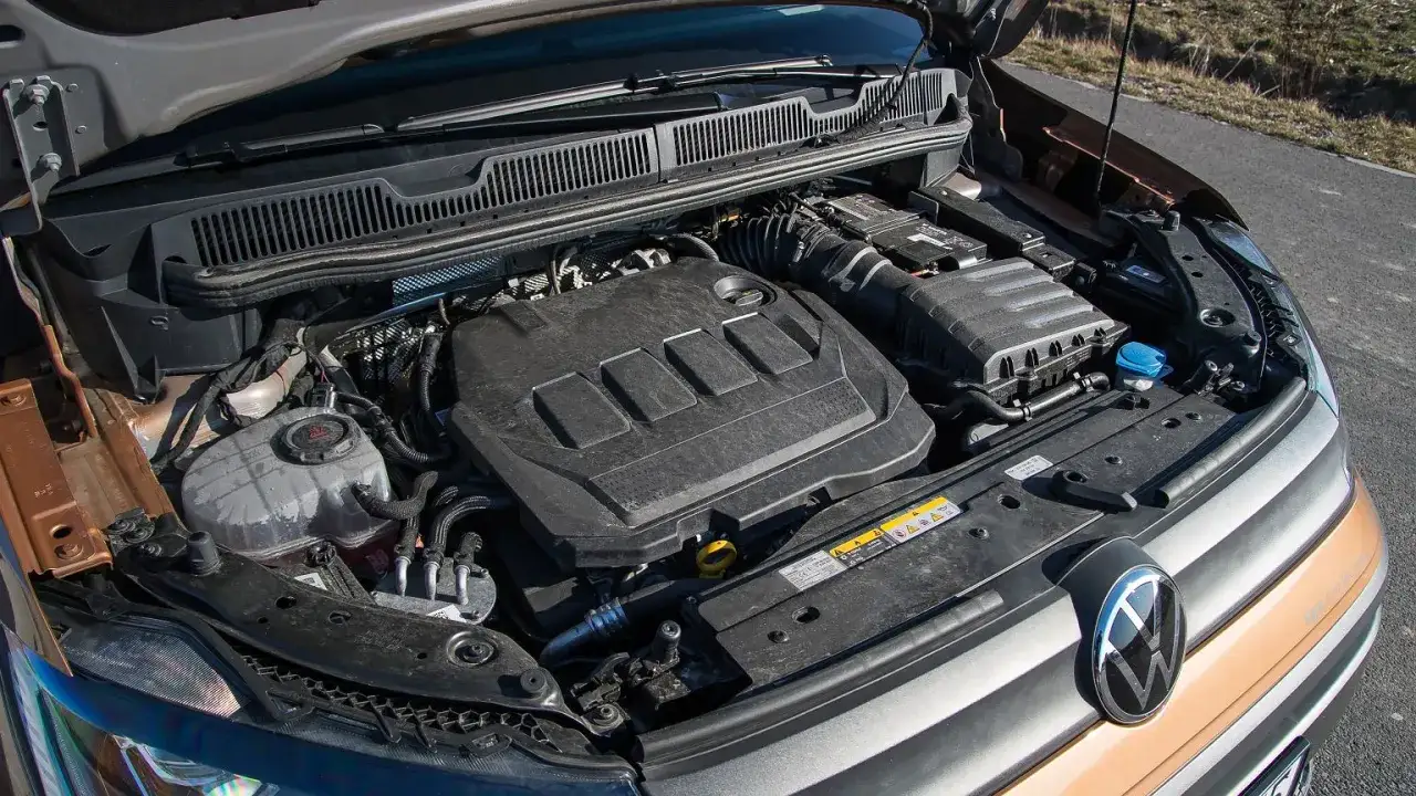 Silnik 1.9 TDI pod maską samochodu. Widoczny czarny plastikowy dekiel silnika z wytłoczeniami.