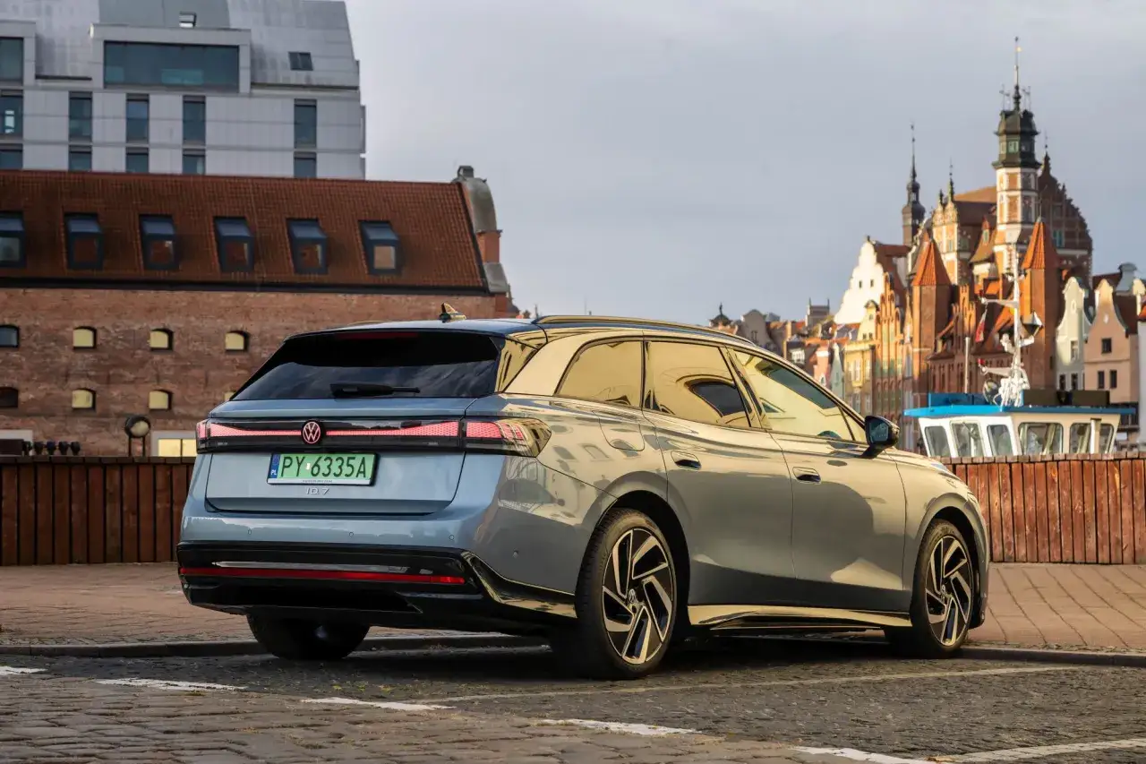 Nowy VW ID.7 w wersji kombi parkuje na bruku, w tle zabytkowa zabudowa i łódź.