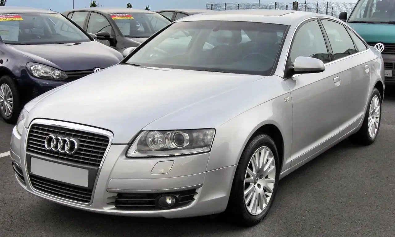Srebrne Audi A6 C6 2.7 TDI na parkingu, obok inne samochody.