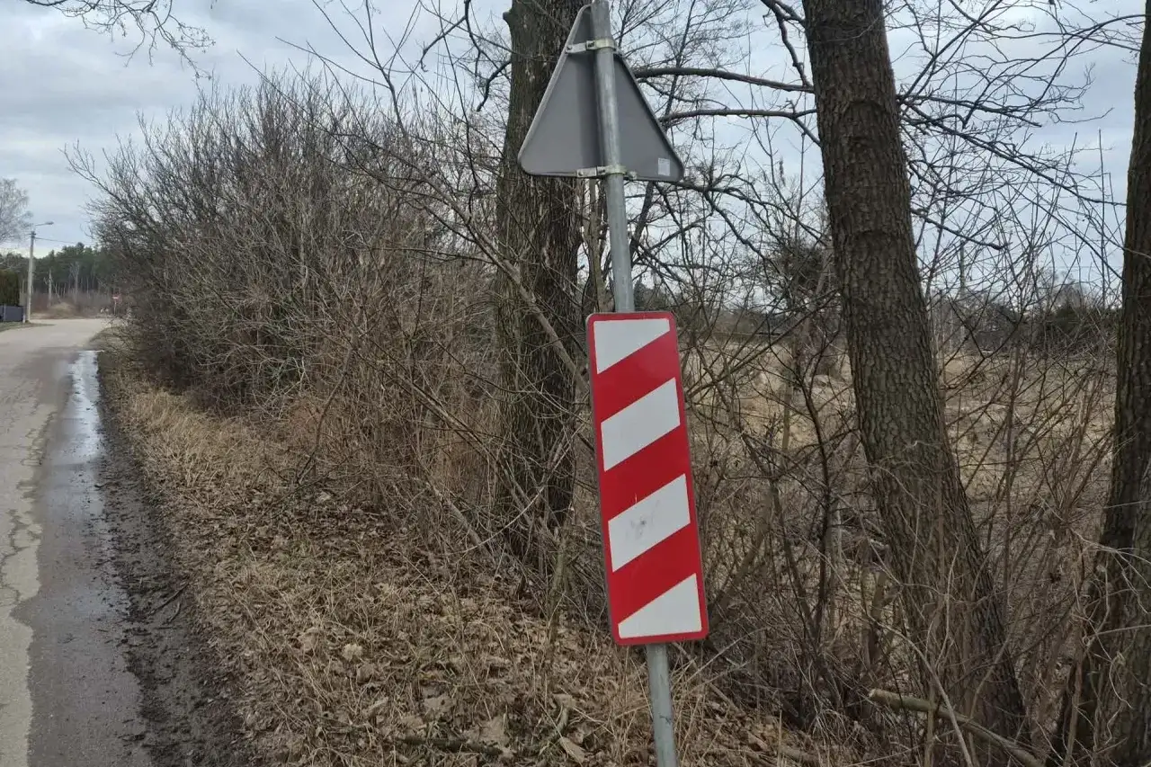 Znak ostrzegawczy przed przejazdem kolejowo-drogowym. Czerwono-białe pasy wskazują zbliżanie się do niebezpiecznego miejsca.