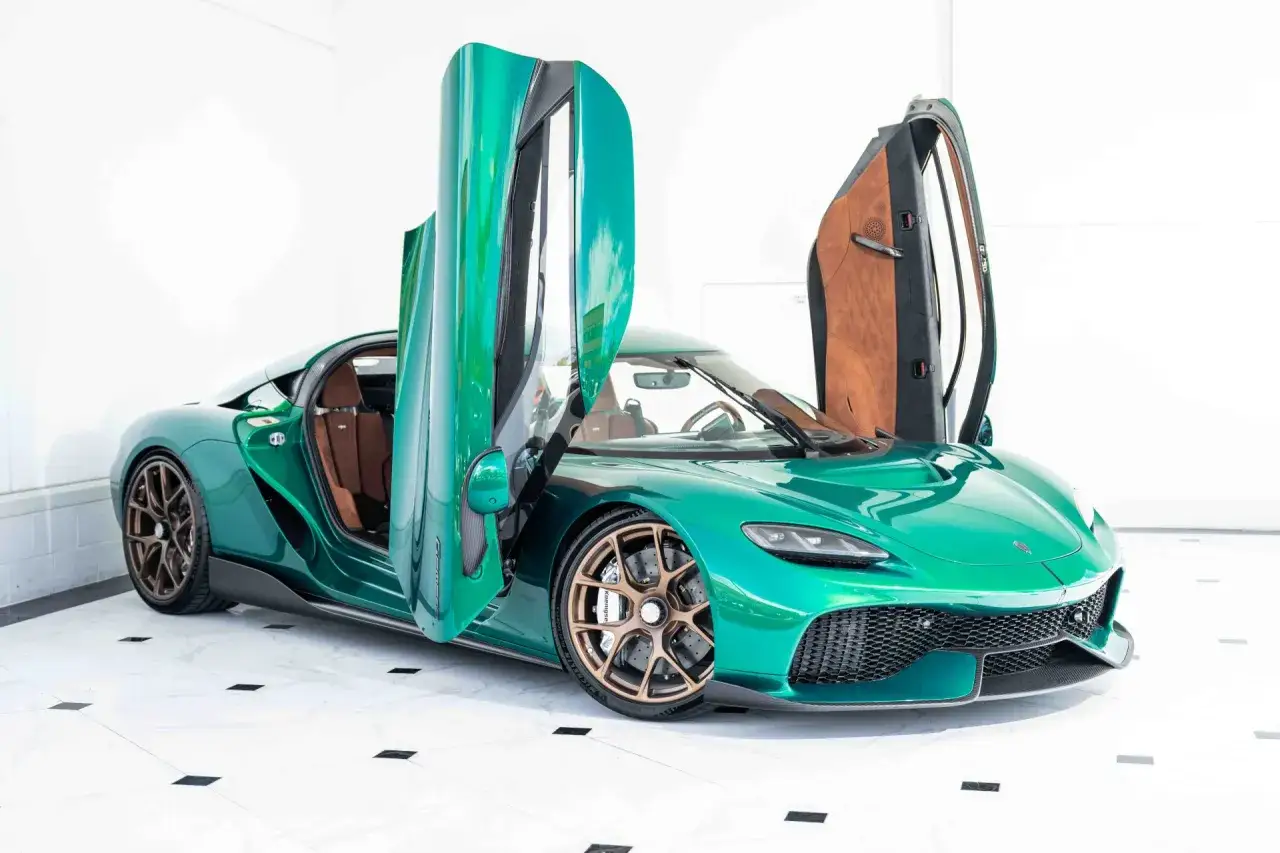 Zielony Koenigsegg Gemera z otwartymi drzwiami, ukazujący luksusowe wnętrze.