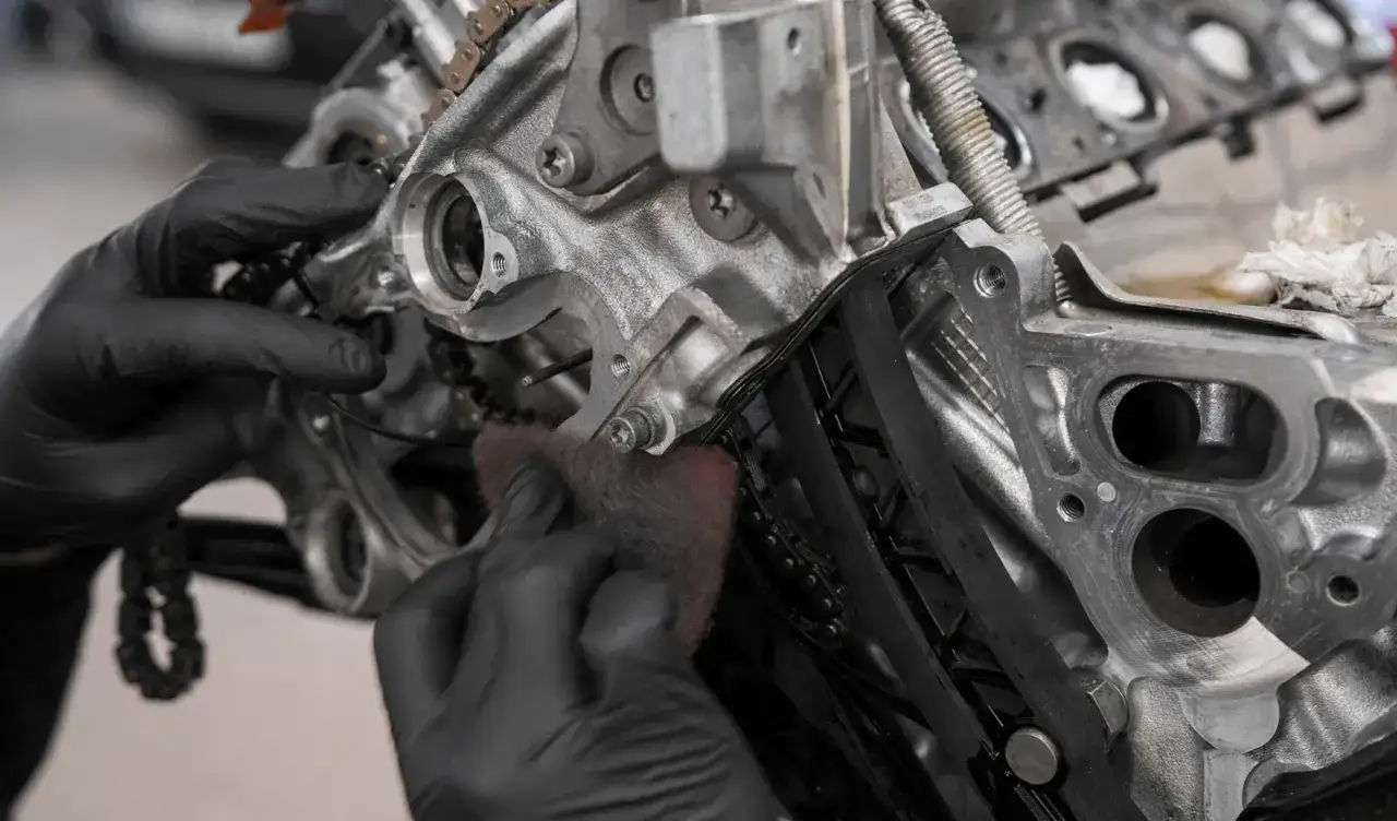 Mechanik w czarnych rękawiczkach czyści elementy silnika n20.