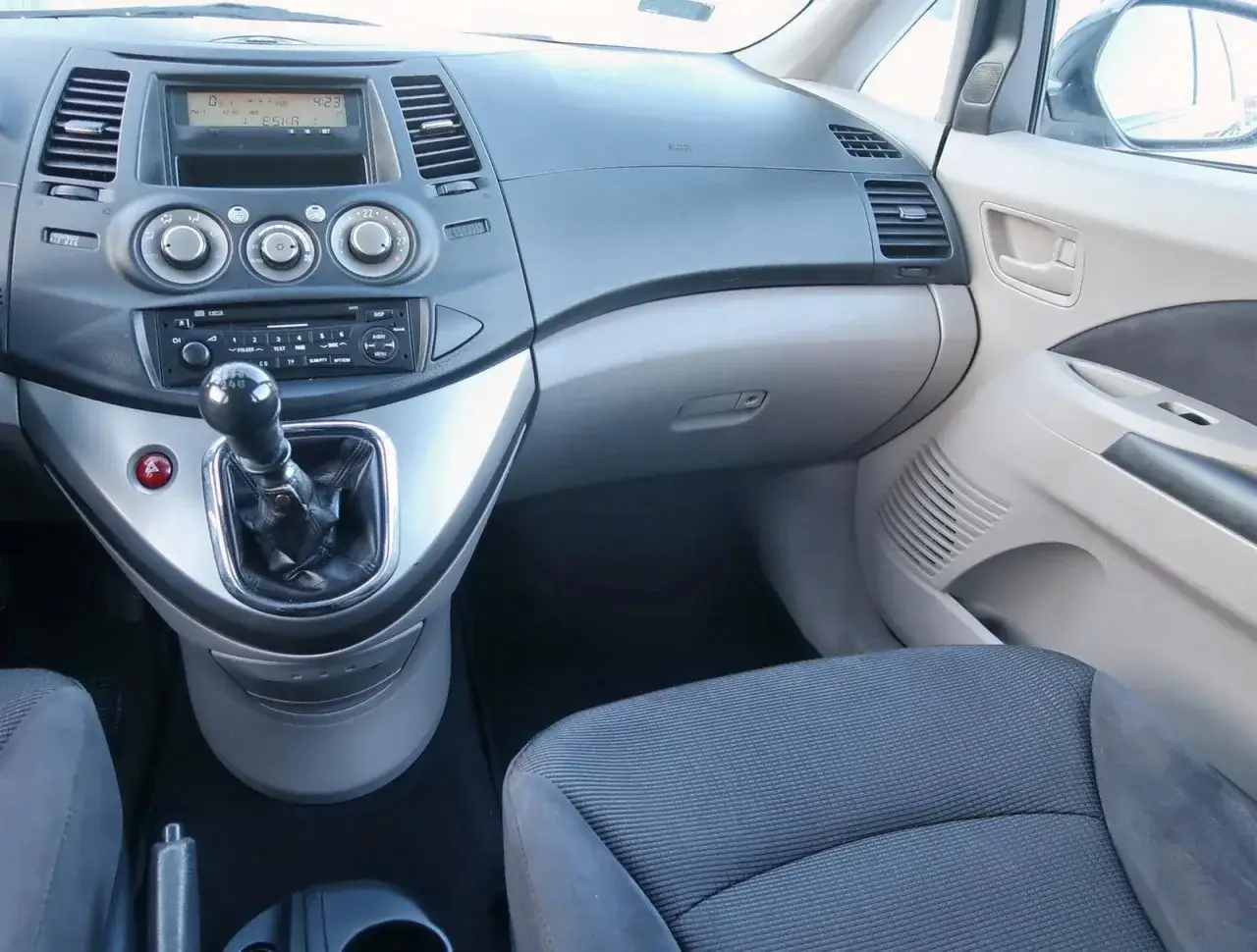Wnętrze Mitsubishi Grandis: dźwignia zmiany biegów, radio, nawiewy i siedzenie pasażera.