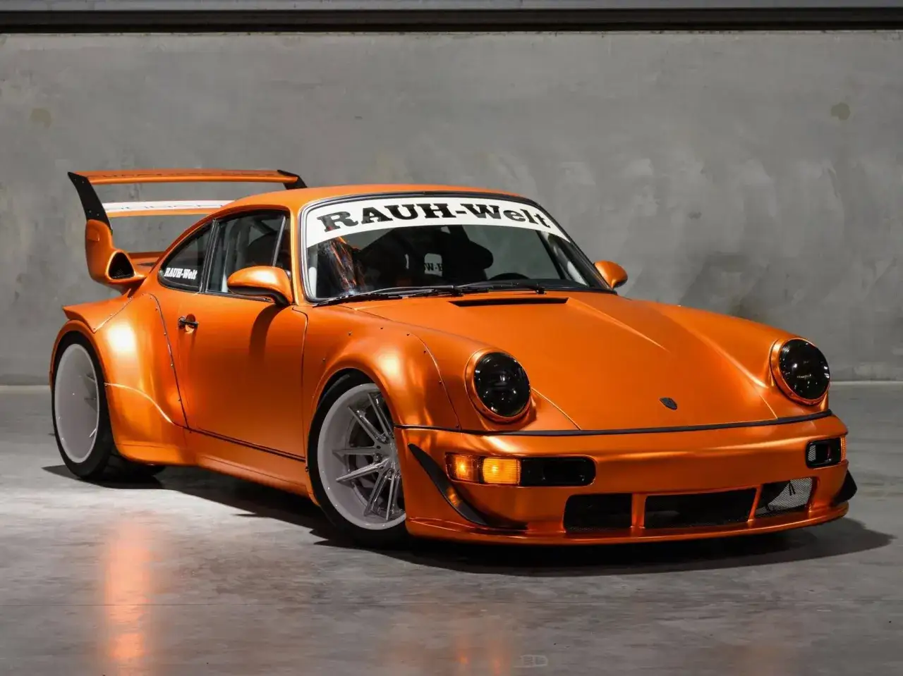 Pomarańczowy Porsche RWB z szerokimi błotnikami i charakterystycznym skrzydłem.