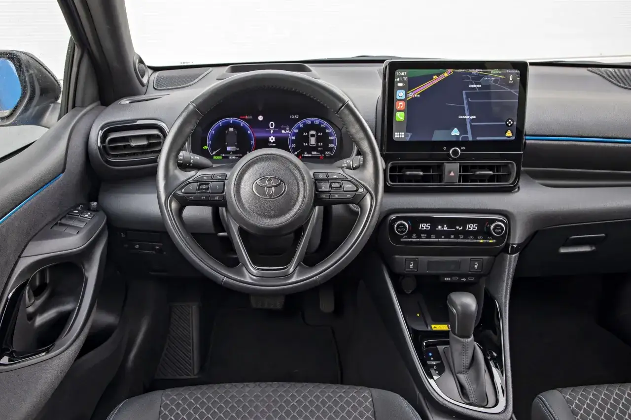 Wnętrze Toyoty Yaris z ekranem nawigacji i cyfrowymi zegarami. Sprawdź aktualną toyota yaris cena i wyposażenie.