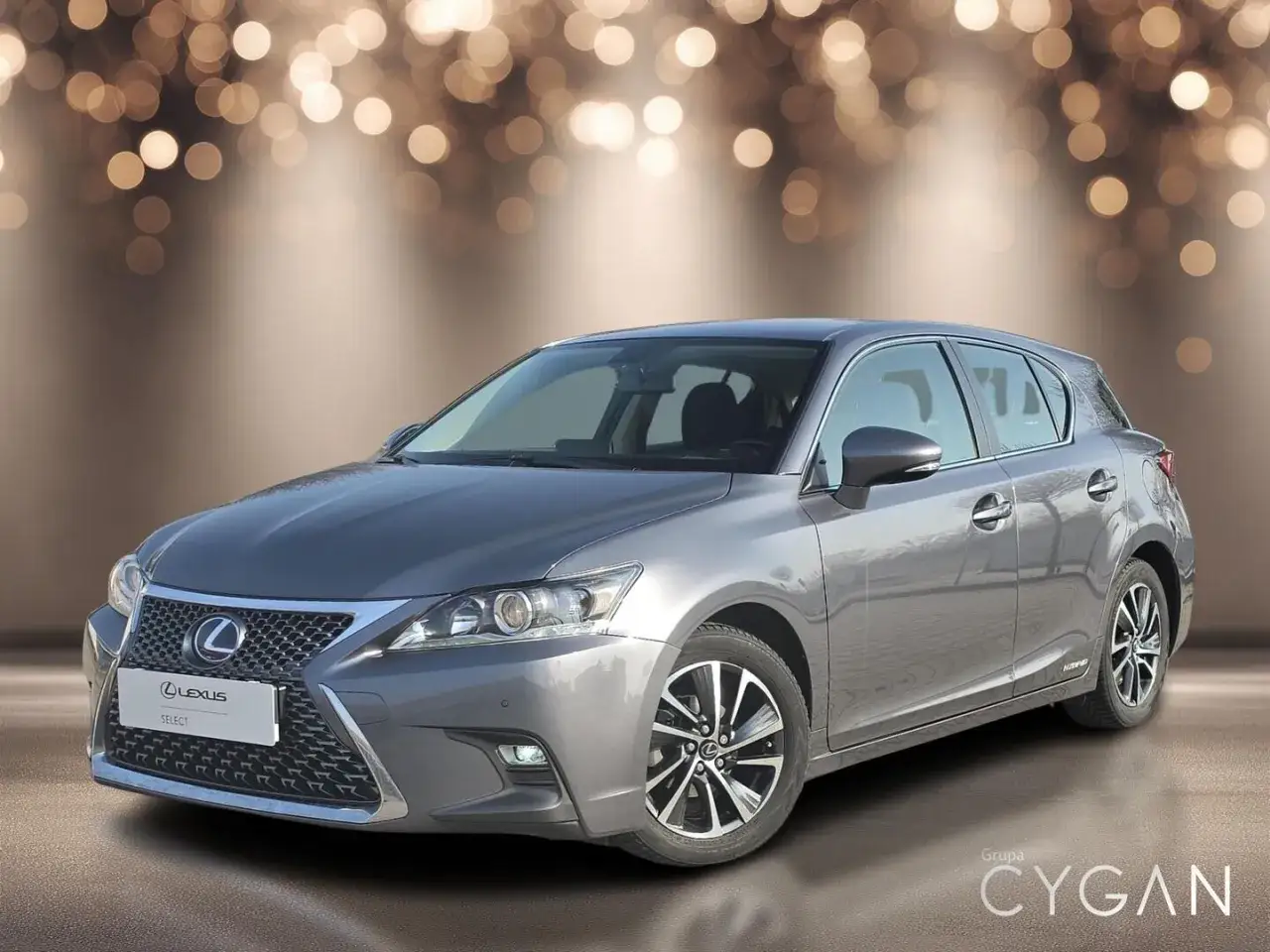 Elegancki, szary Lexus CT 200h z pięknym tłem w postaci świateł. Idealny do miasta i na dalsze trasy.