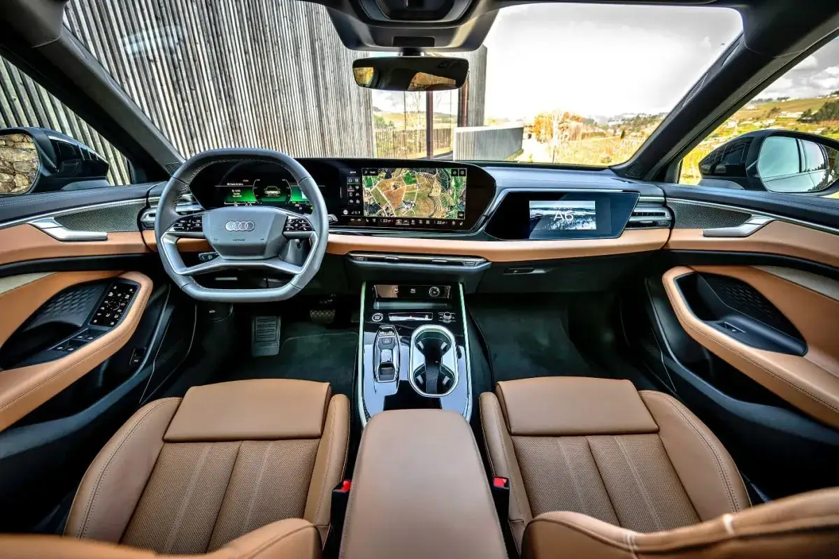 Wnętrze Audi A6 C9 z brązową skórzaną tapicerką, nowoczesnym kokpitem i ekranem nawigacji.