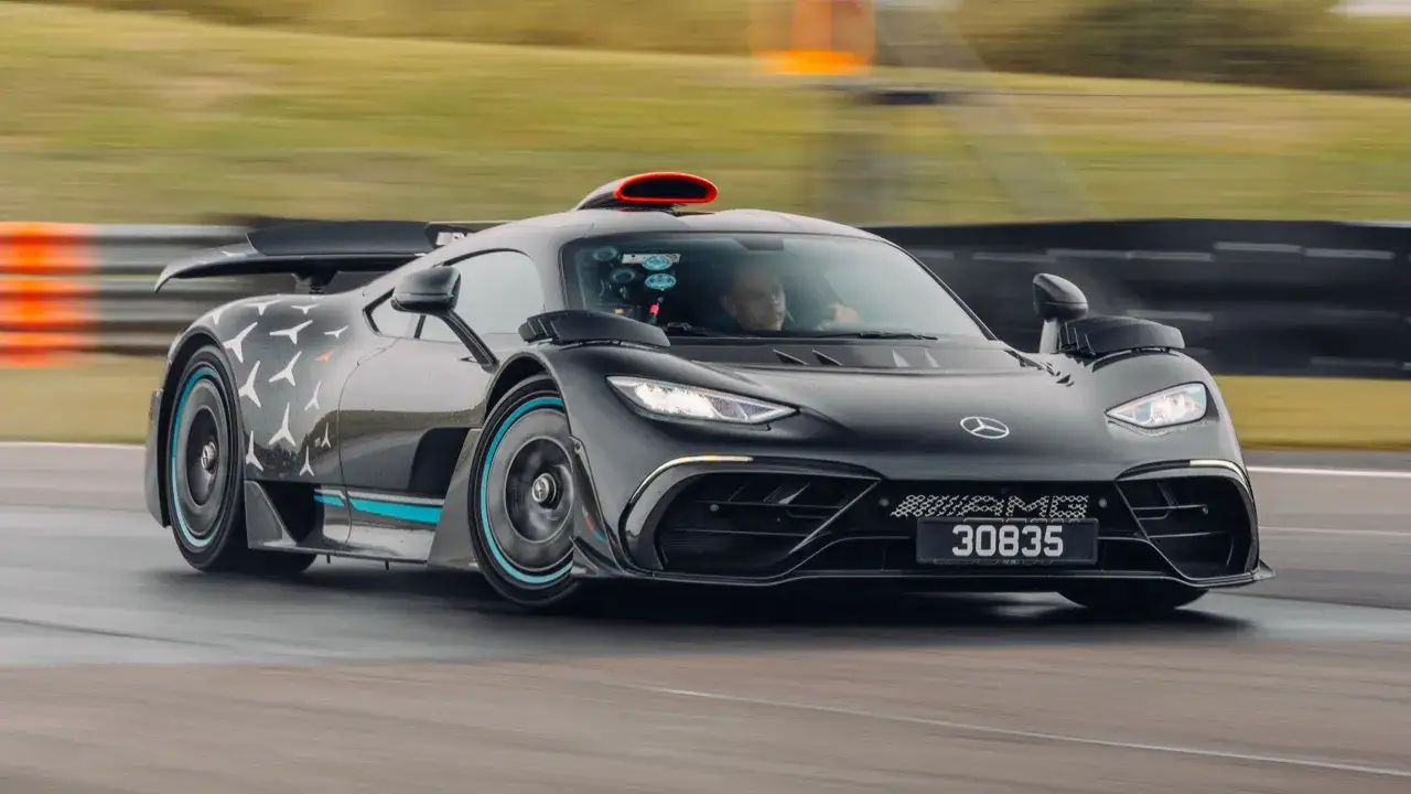 Czarny Mercedes-AMG Project One pędzi po torze, z czerwonym wlotem powietrza na dachu i białymi symbolami na karoserii.