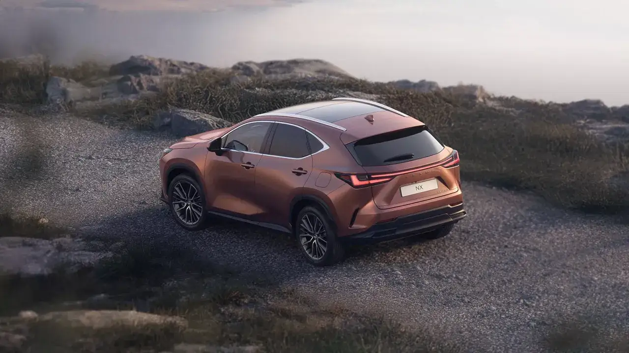 Brązowy Lexus NX 450h+ na kamienistej drodze. Sprawdź jego atrakcyjną cenę i możliwości terenowe.
