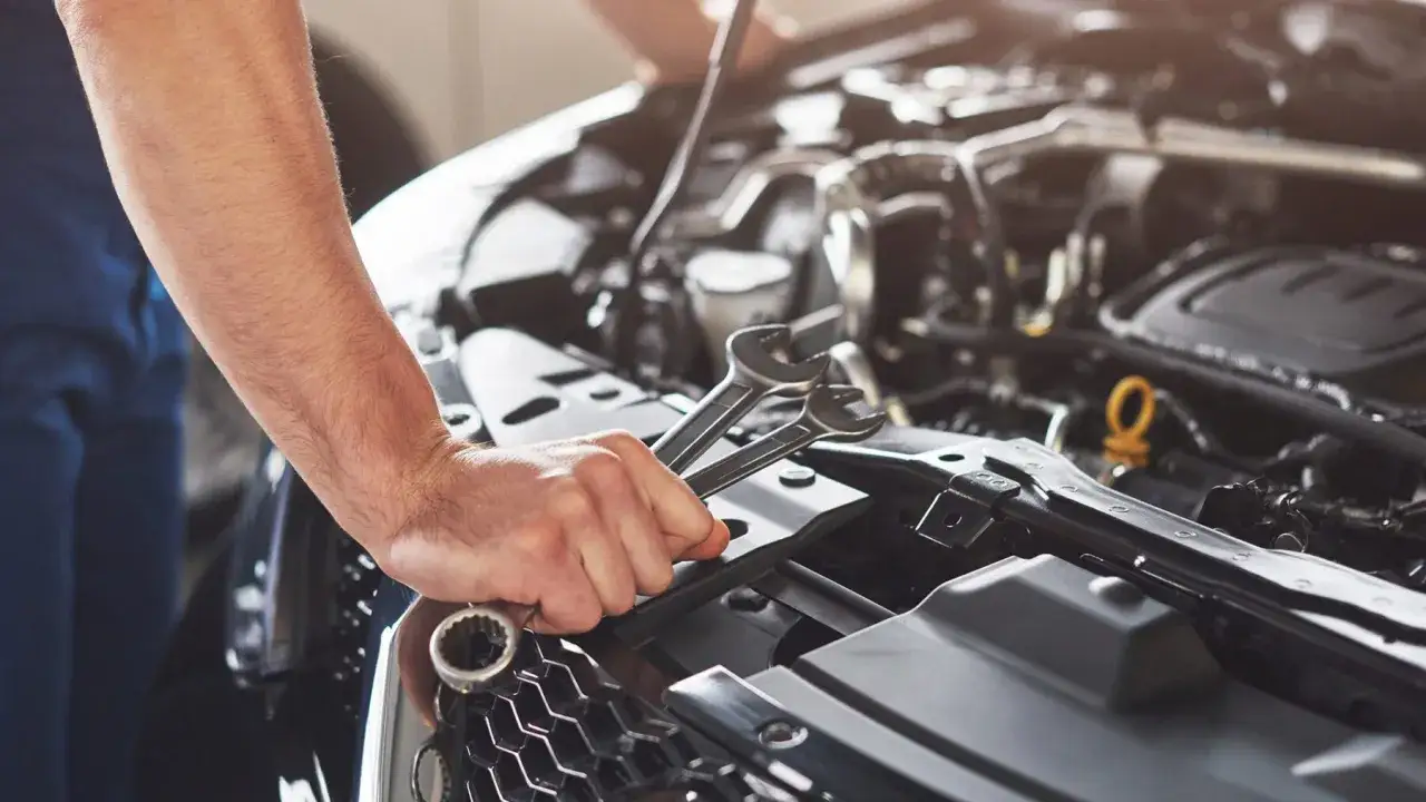 Mechanik z kluczami w dłoni diagnozuje nierówną pracę silnika.