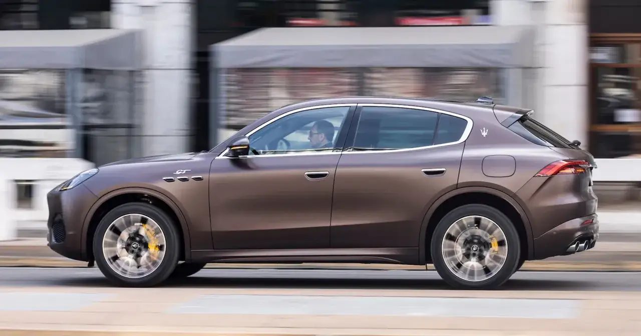 Brązowy Maserati Grecale GT w ruchu miejskim. Kierowca w okularach prowadzi luksusowego SUV-a.